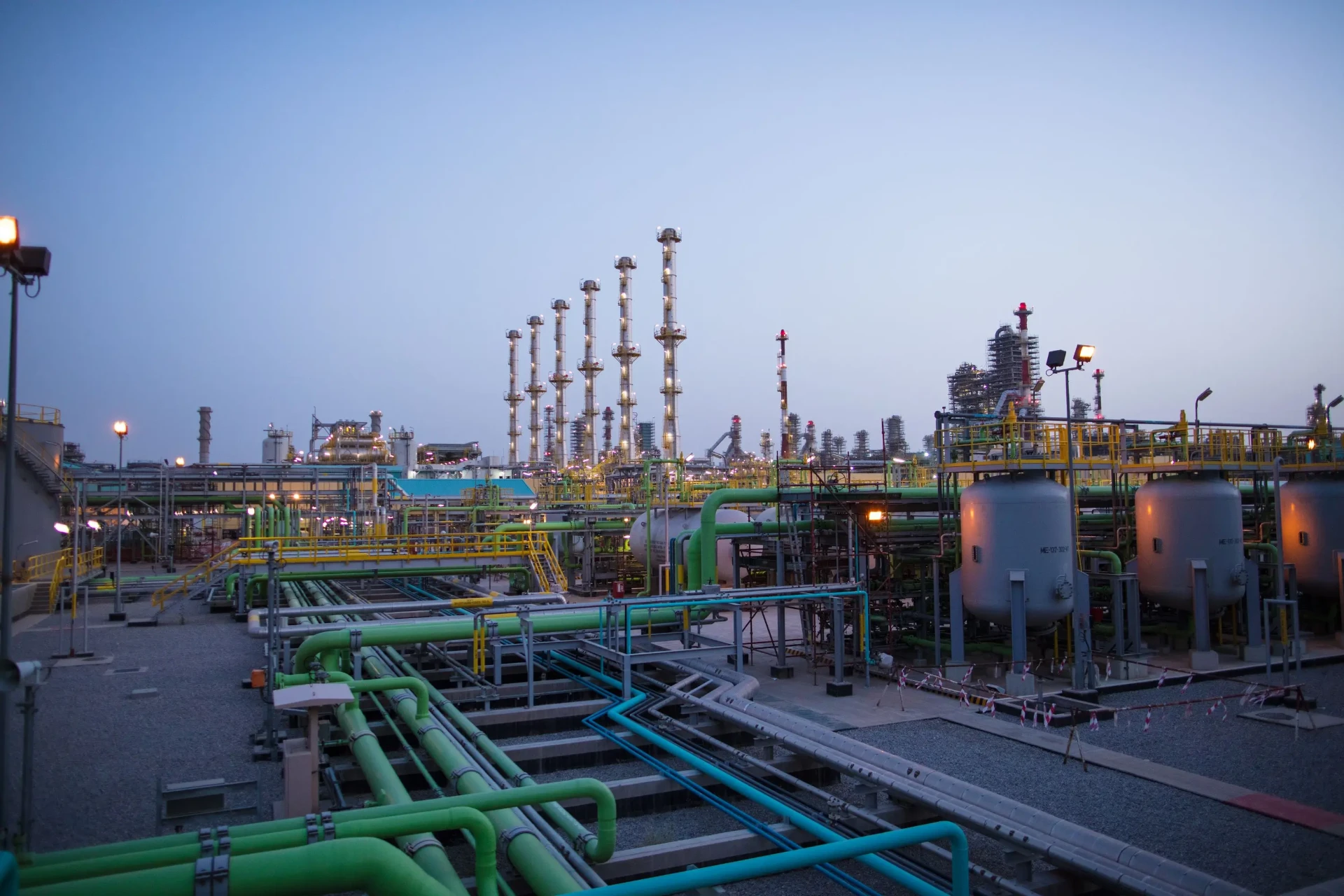 Industrial refinery at night with illuminated processing towers and pipeline infrastructure