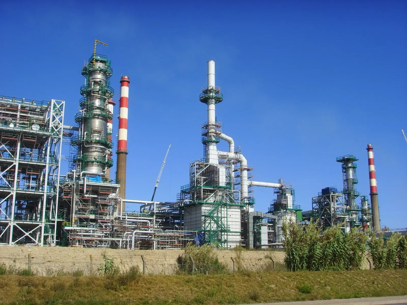 Industrial refinery conversion showing distillation towers and processing units under a clear sky